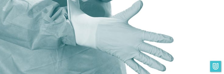 Medical worker in PPE donning Unigloves disposable latex gloves.